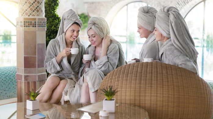 Four young happy women drinking tea at spa resort.